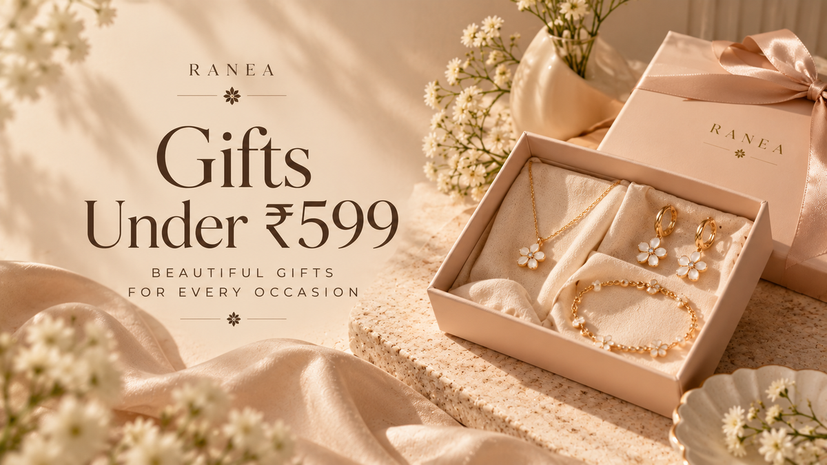 Gold-tone necklaces, earrings, rings and bracelets arranged on soft beige satin for an affordable jewellery gift guide.